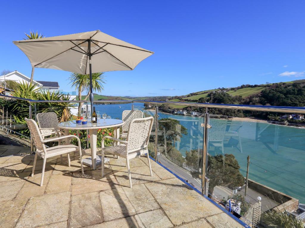 a patio with an umbrella and a table and chairs at 2 Channel View in Salcombe