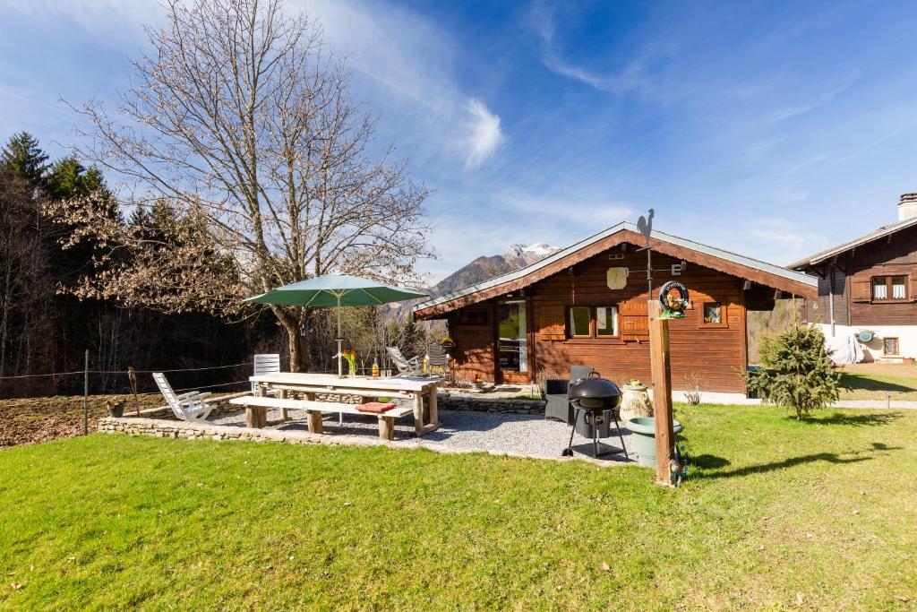 a log cabin with a picnic table and an umbrella at Sauvage in Les Combes