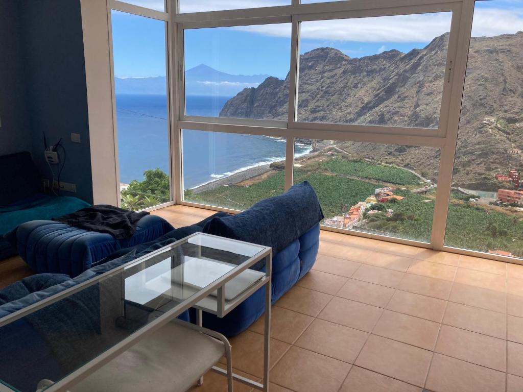 a living room with a blue couch and a view of the ocean at Casa Julietta in Hermigua