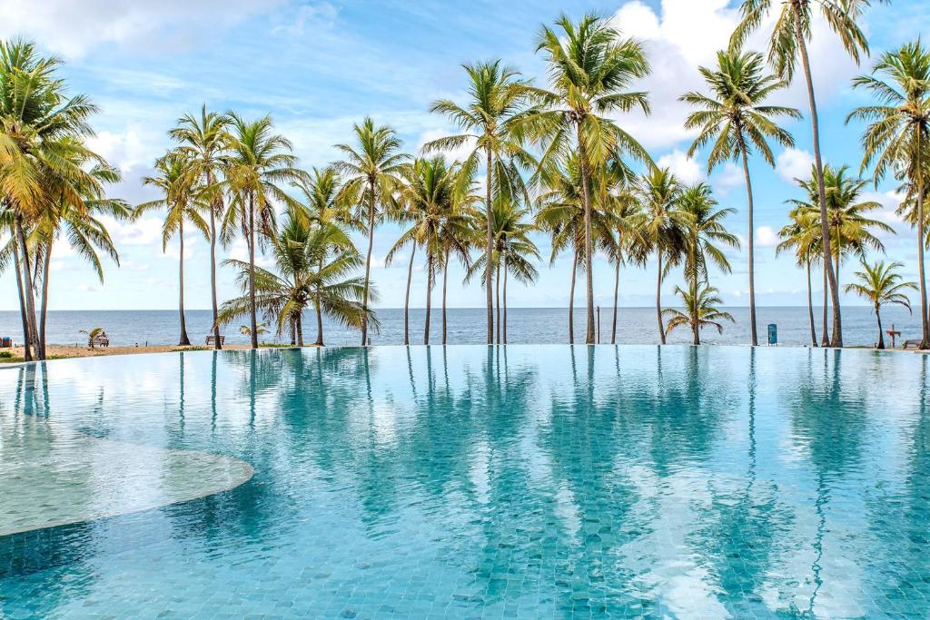 uma piscina com palmeiras e praia em Sauipe Grand Premium Brisa - All Inclusive na Costa do Sauípe