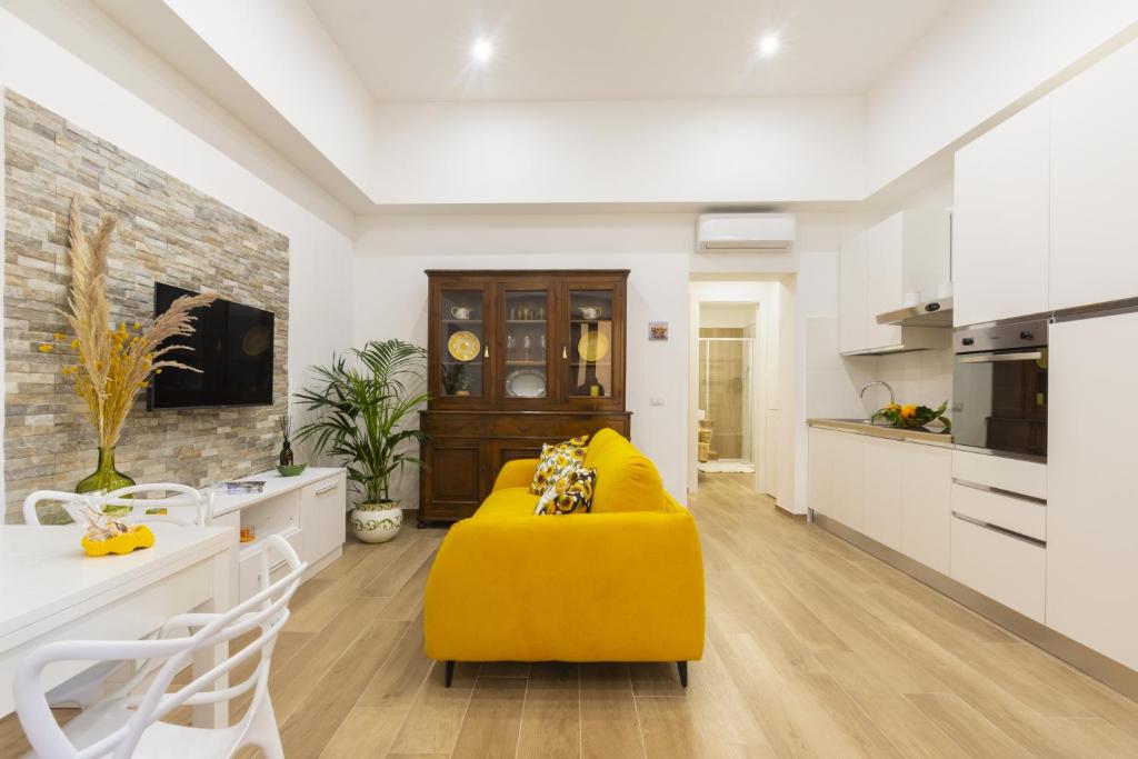 a living room with a yellow couch and a kitchen at Mirasole House in Massa Lubrense