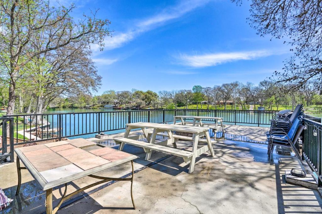 a patio with two picnic tables and a fence at Waterfront Guadalupe River Lodge Home with Dock! in Seguin