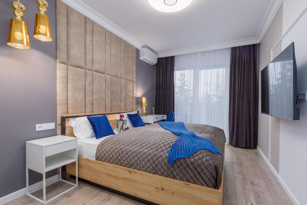 1 dormitorio con 1 cama grande con almohadas azules en Wellness Resort & SPA Mermaid Apartments with Parking by Renters Prestige, en Dziwnów