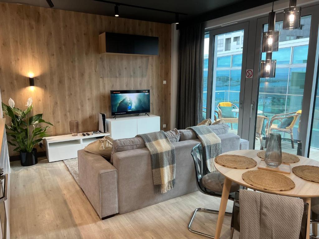 グディニャにあるModern Vero Apartments Yacht Parkのリビングルーム(ソファ、テレビ、テーブル付)