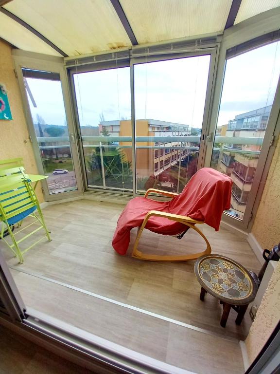 Cette chambre dispose d'un balcon avec une chaise et des fenêtres. dans l'établissement Appartement accueillant à Mandelieu-la-Napoule 32 m² avec balcon, à Mandelieu-la-Napoule