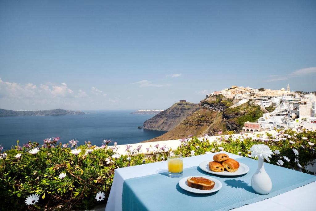 stół z dwoma talerzami jedzenia i widokiem na ocean w obiekcie The Atlantis House w Firze