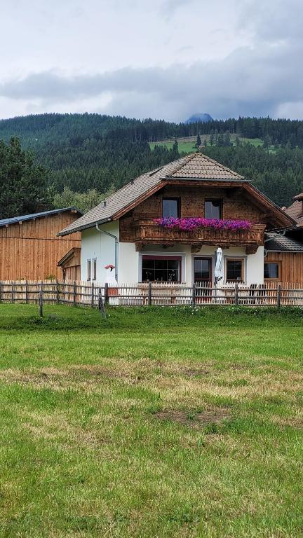a house with flowers on the front of a field at Chalet Hoamat in Mariapfarr