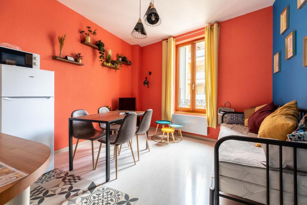 a living room with orange walls and a table and chairs at Lisboa F3 Centre-ville Clermont-Fd C in Clermont-Ferrand