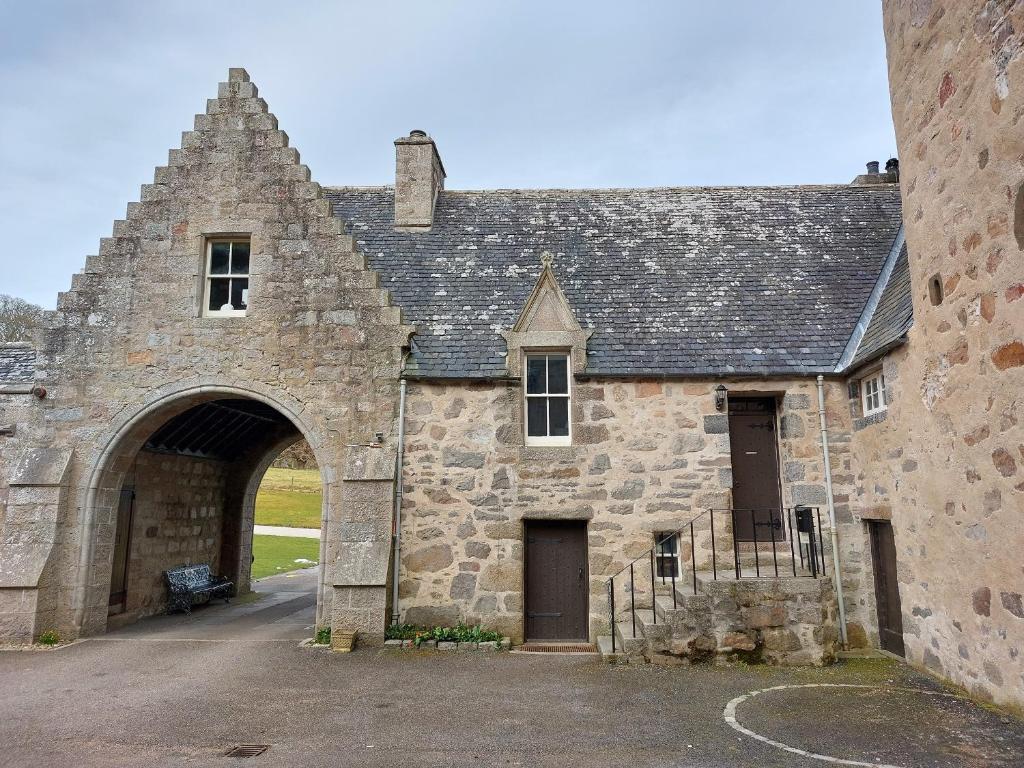 un antiguo edificio de piedra con un gran arco en Courtyard Cottage - Drum Castle en Banchory