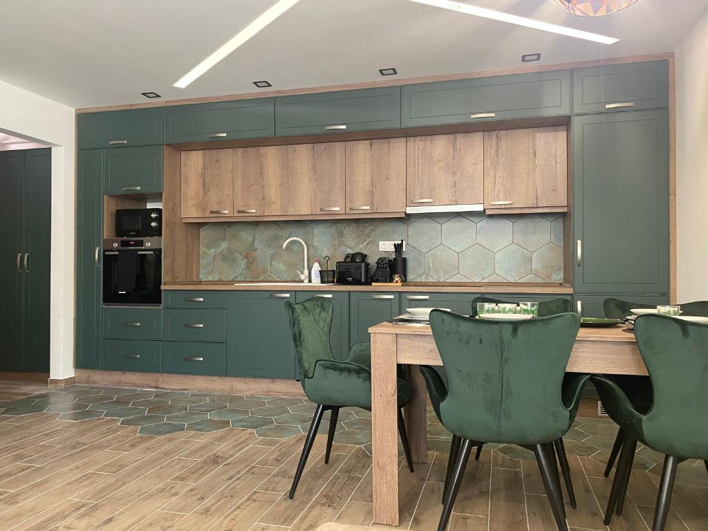 une cuisine avec une table en bois et des chaises vertes dans l'établissement Sunshine Homes Luxury Apartmanok, à Zamárdi