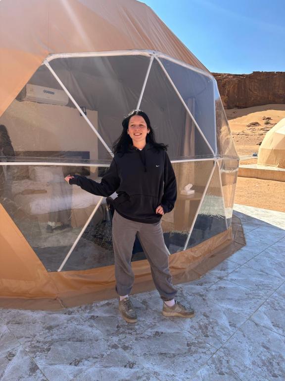 Una donna è in piedi dentro una tenda di Darien Luxury Camp a Wadi Rum