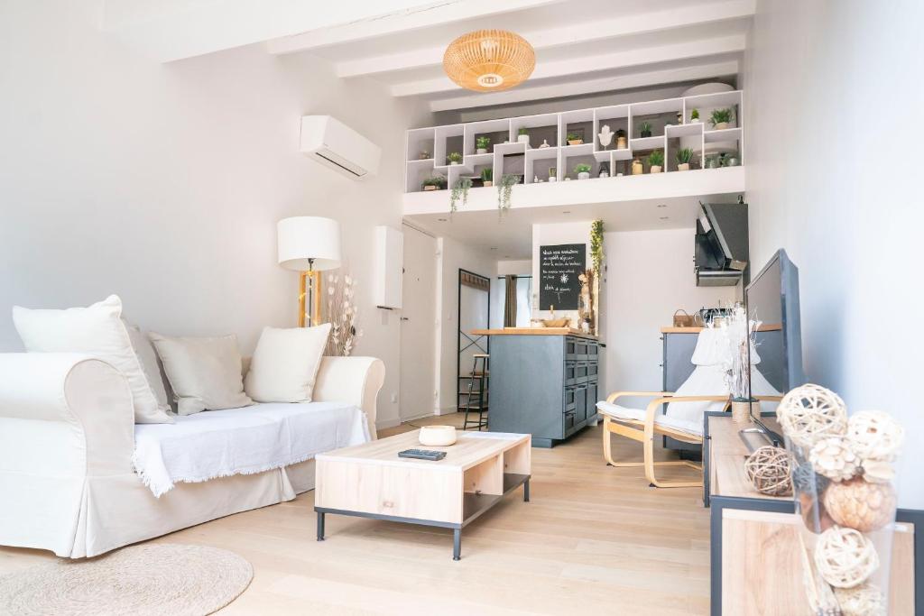 a living room with a white couch and a table at Maison chaleureuse à 5 mins des remparts in Aigues-Mortes