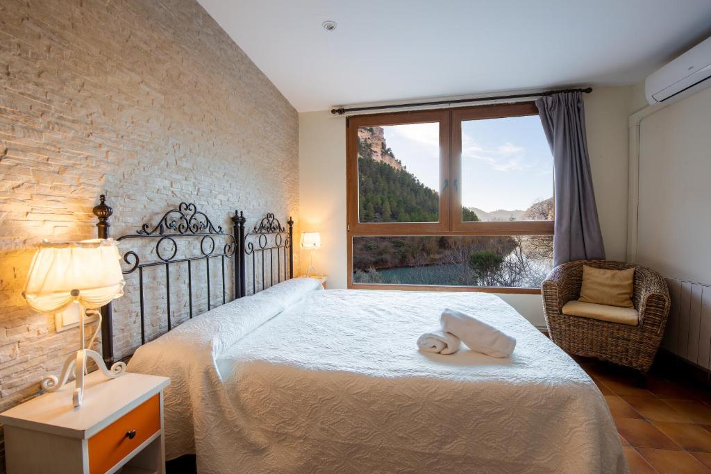 Hostal Avenjúcar في Tolosa: غرفة نوم بسرير مع نافذة وكرسي