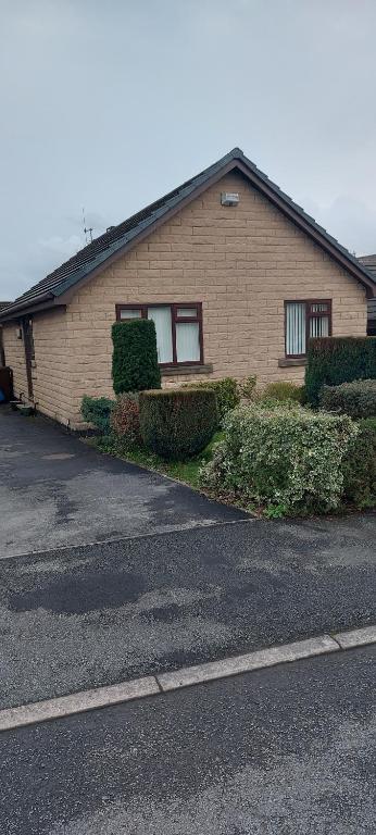 a brick house with a parking lot in front of it at The Bungalow in Longdendale