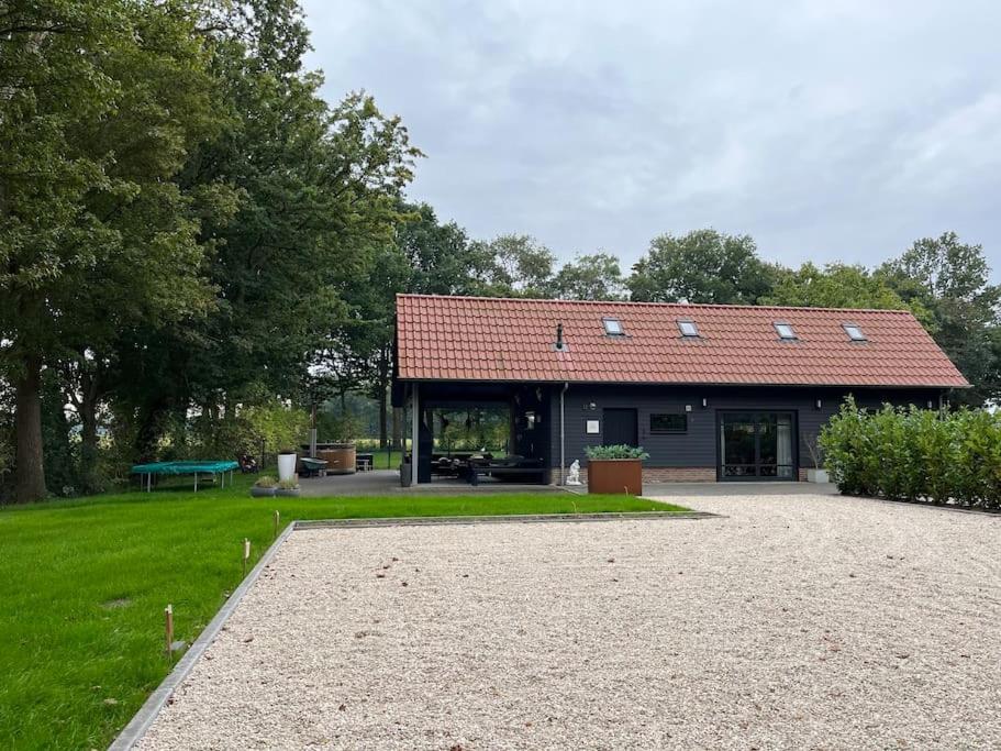 a building with a red roof in a park at Landelijk gelegen vakantiehuis met hottub! in Tollebeek