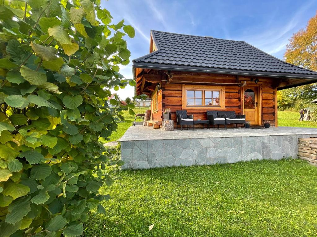 eine Blockhütte mit einer Terrasse im Gras in der Unterkunft Domek Wałacha in Istebna