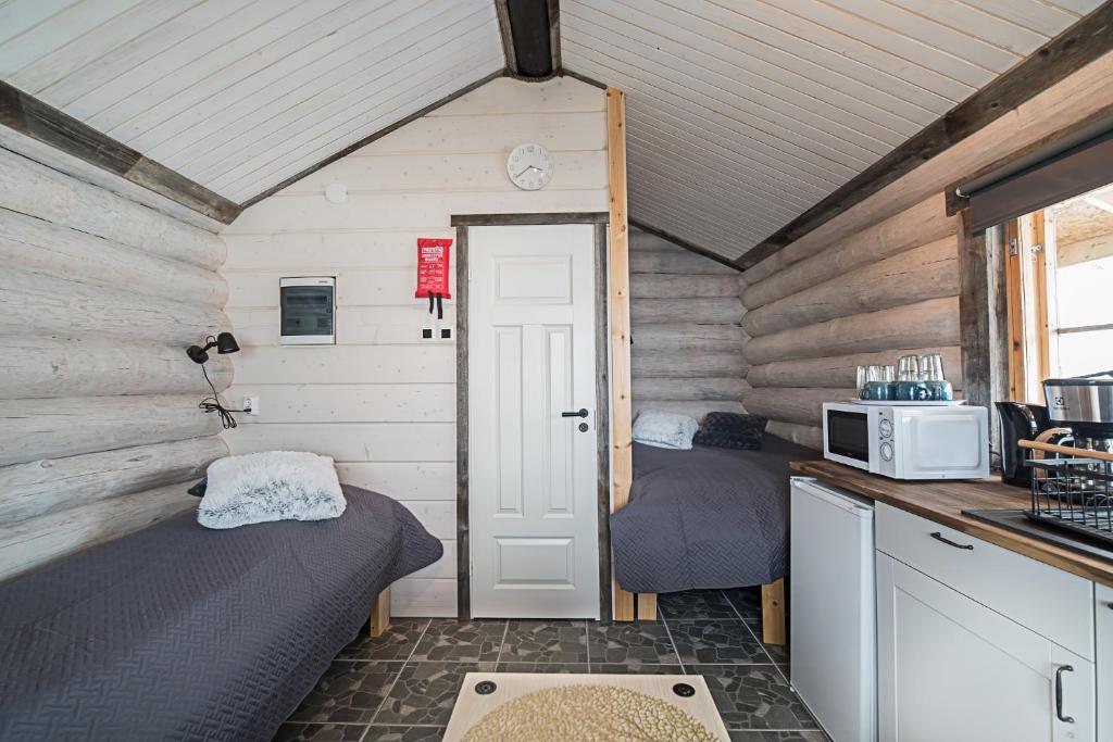 Kleines Zimmer mit 2 Betten und einer Mikrowelle in der Unterkunft Naali Mökki in Kilpisjärvi