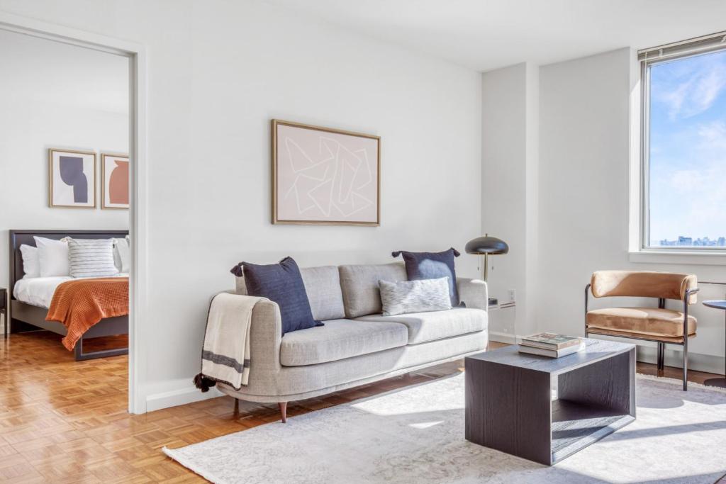 una sala de estar con un sofá y una cama en LIC 2BR w WD Elevator Doorman nr E River NYC-766, en Nueva York