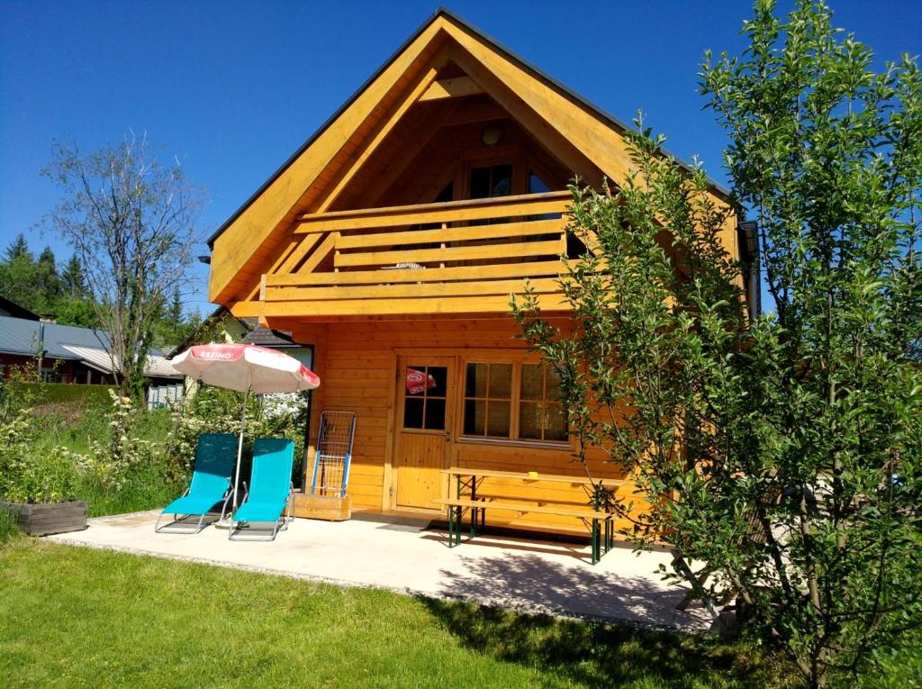 eine Hütte mit 2 Stühlen und einem Sonnenschirm in der Unterkunft Faakersee - Familyhouse - mit PrivatStrand- Only Sa-Sa in Egg am Faaker See