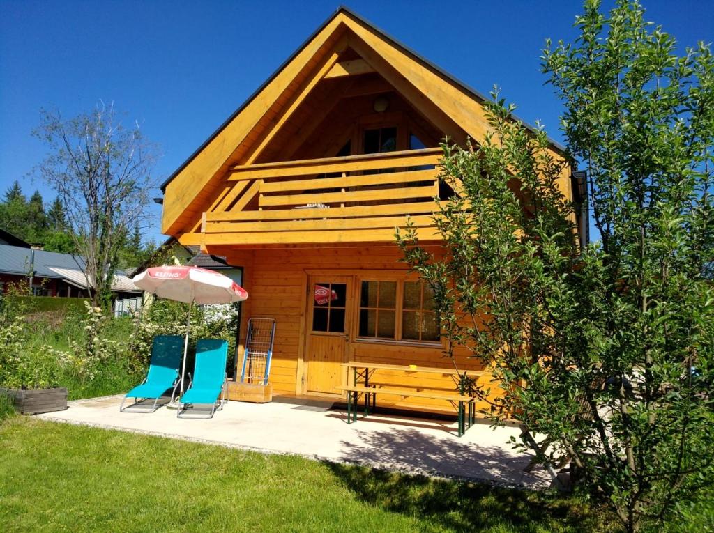 a cabin with two chairs and an umbrella at Faakersee - Familyhouse - mit PrivatStrand- Only Sa-Sa in Egg am Faaker See