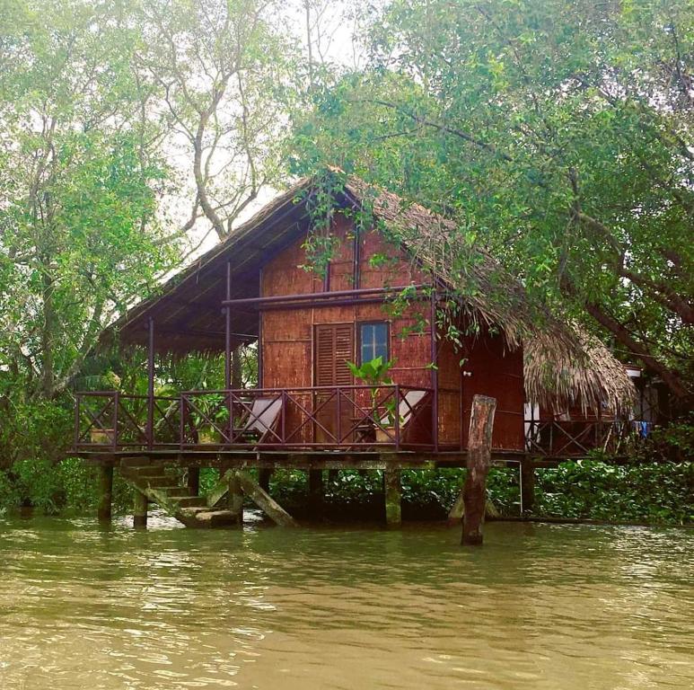 une maison en bois sur une jetée dans l'eau dans l'établissement Happy Family Guesthouse, à Vĩnh Long