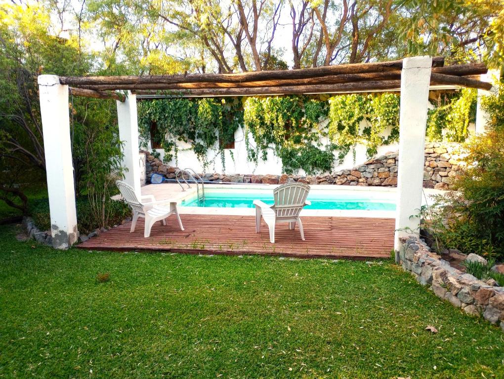 pérgola con 2 sillas, mesa y piscina en Aires de Coria en Chacras de Coria