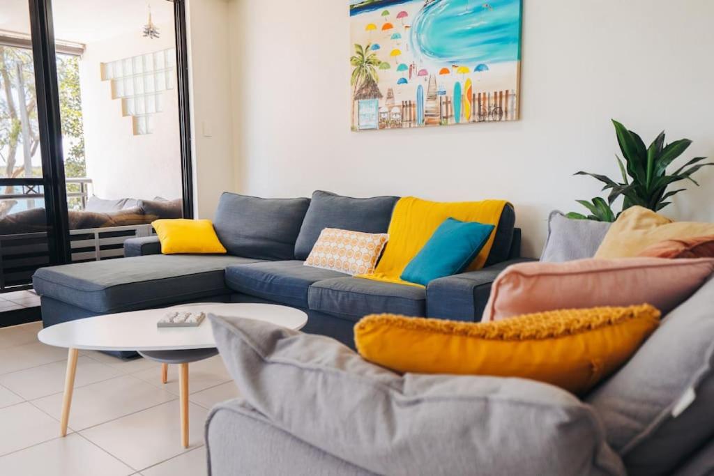a living room with a blue couch and yellow pillows at Waterfront Apt Maroochy River in Maroochydore