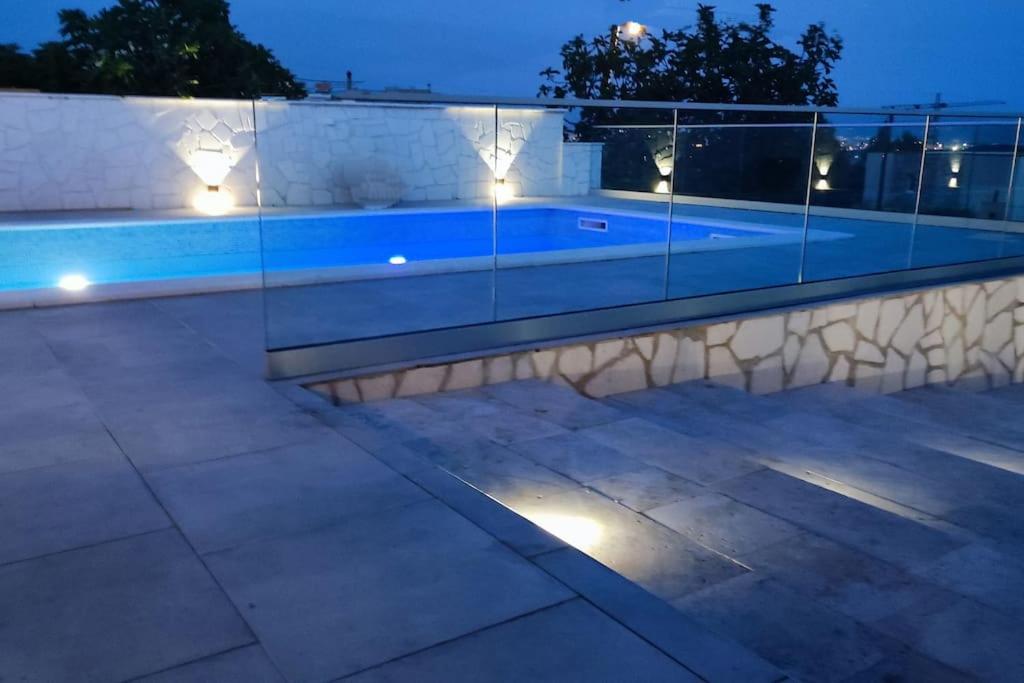 una piscina en una casa por la noche con luces en Holiday house Doris with pool, garden and view, en Kaštela