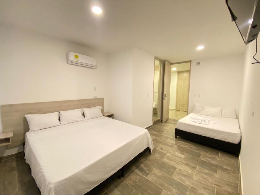 San AlbertoにあるHOTEL COLOMBIA BYBのベッドが2つと鏡があるホテルの部屋