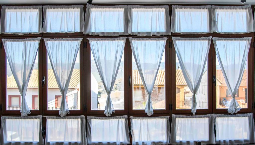un grupo de ventanas con cortinas blancas en una habitación en La Balconera de Ana en Puebla de Don Rodrigo