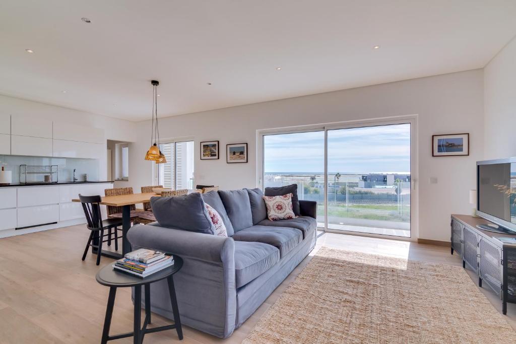 a living room with a blue couch and a kitchen at FormosaFuzeta Seaview @Homesbyfc in Fuzeta
