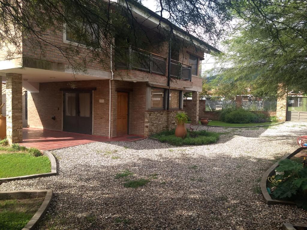 a brick house with a gravel driveway in front of it at Los algarrobos in Villa Carlos Paz