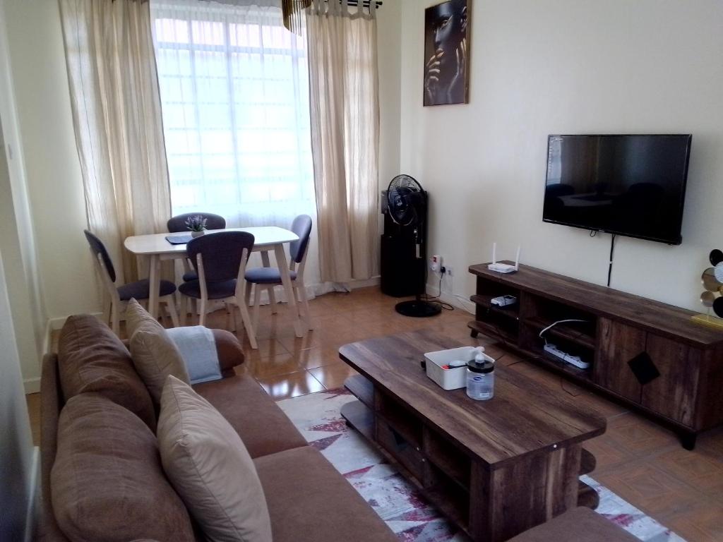 a living room with a couch and a tv and a table at Tranquil haven - spacious, cozy, 1 bedroom in Kisumu