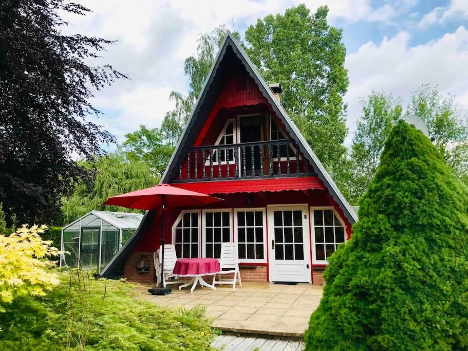 una piccola casa con il tetto rosso e le sedie rosse di Ferienhaus am Mescheriner See a Mescherin