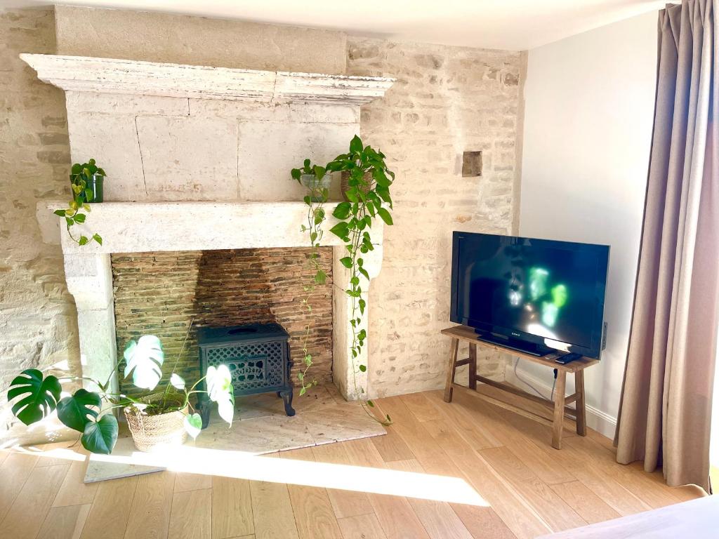 ein Wohnzimmer mit einem TV und einem gemauerten Kamin in der Unterkunft La Grange 1743 