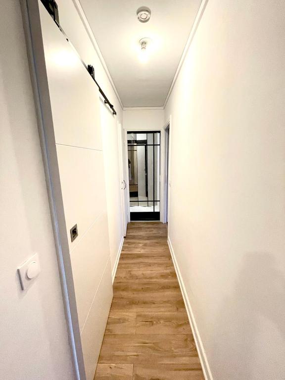 a hallway with white walls and a wooden floor at Appt vu sur un parc privatif à 20 min de Paris in Saint-Leu-la-Forêt
