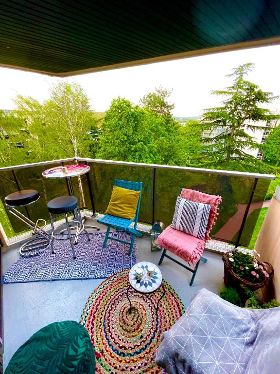 a patio with two chairs and a table and a rug at Appt vu sur un parc privatif à 20 min de Paris in Saint-Leu-la-Forêt
