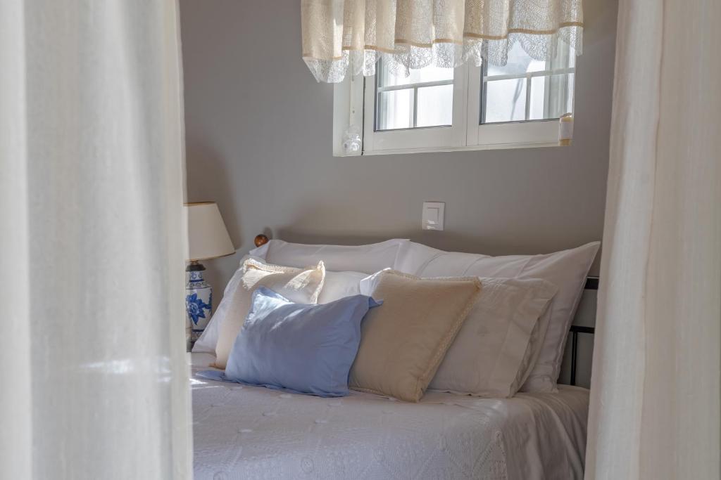 a white bed with white pillows and a window at Heliotropio in Kalamaki