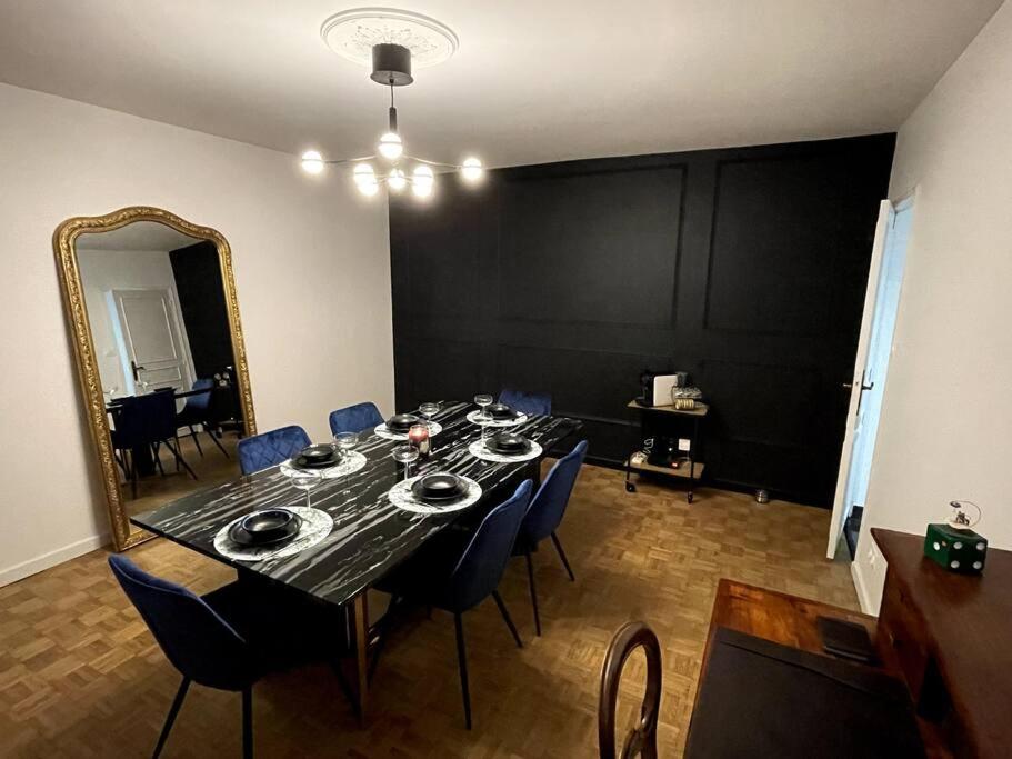 a dining room table with blue chairs and a mirror at Love Games in Plérin