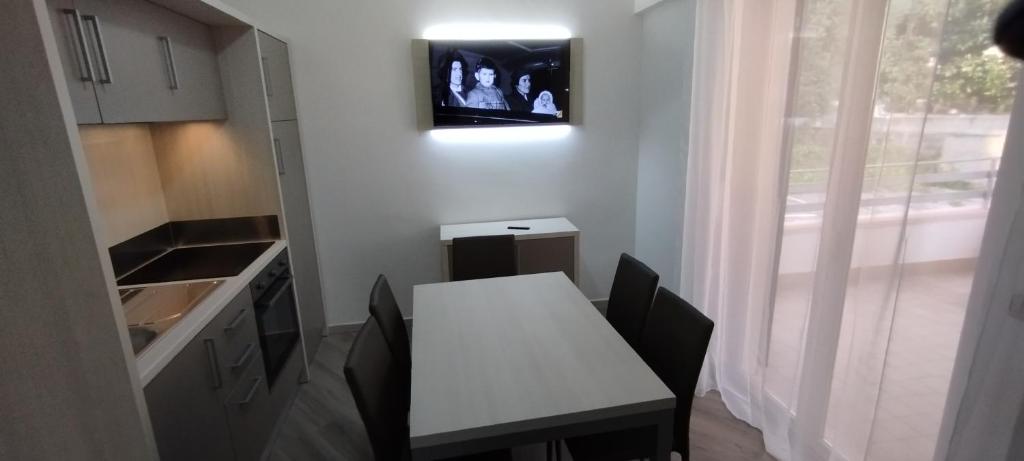 a small kitchen with a table and a tv on the wall at Appartamento Parco Urciuolo Cirella in Cirella