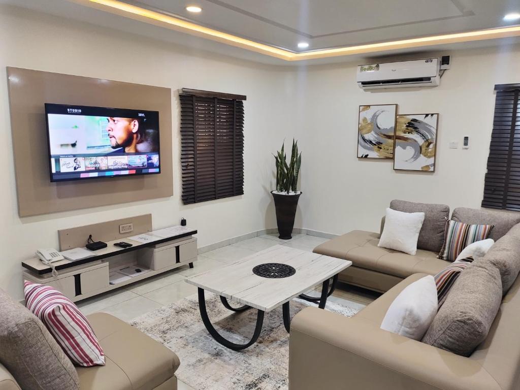 a living room with two couches and a flat screen tv at The Leneade in Abuja