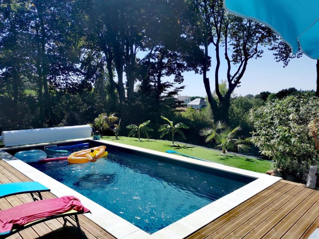 a swimming pool in a backyard with a wooden deck at LA CLOSERIE DE NOINTOT in Nointot