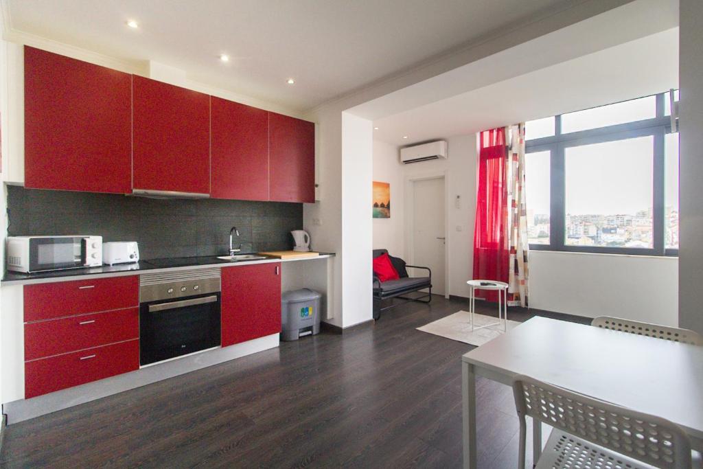 a kitchen with red cabinets and a table in a room at Casa Viveiros do Bairro Penha de França Lisboa in Lisbon