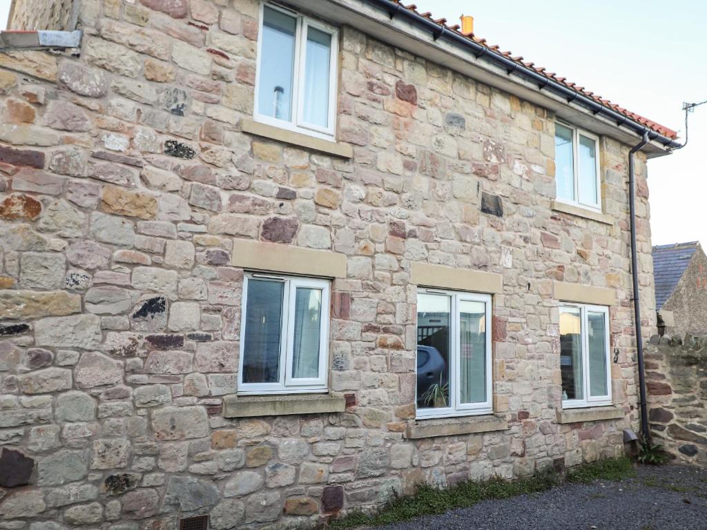 a stone house with three windows on the side of it at Coastal Nest 30 Union Street in Seahouses