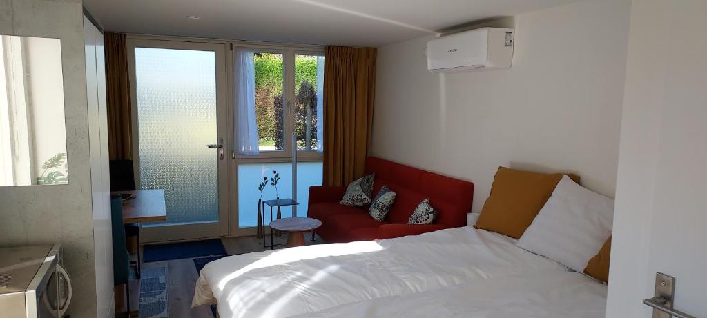 a bedroom with a bed and a red chair and window at Dajan in Almere