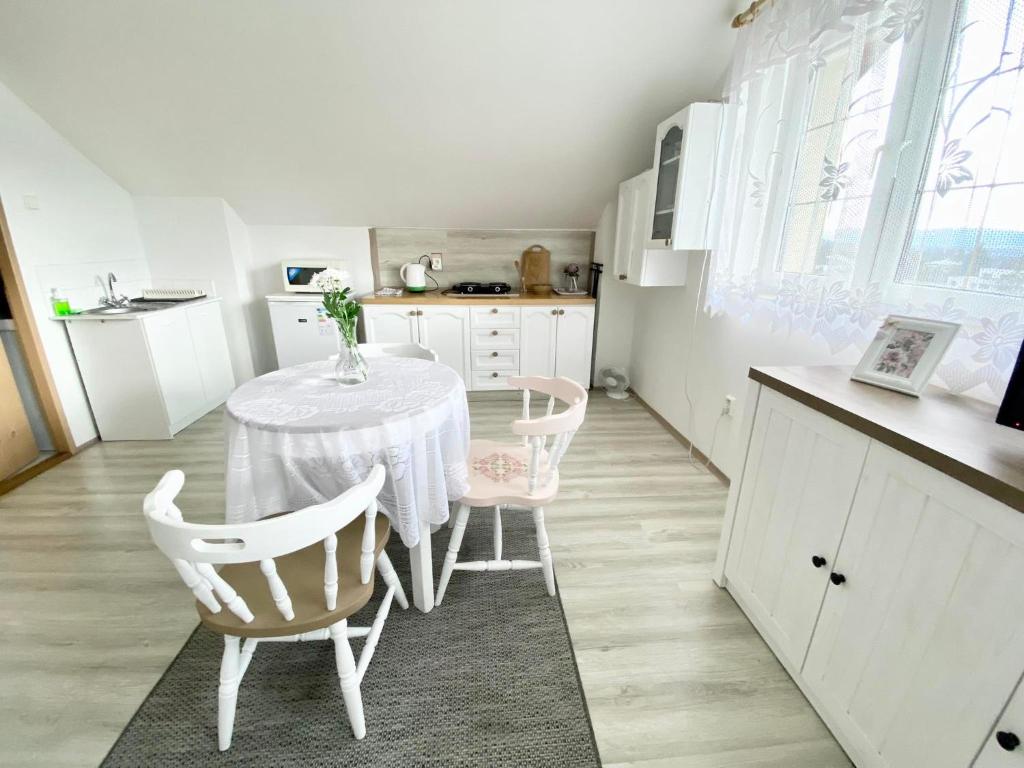 a white kitchen with a table and two chairs at Ubytovani v Beskydech in Bystrzyca