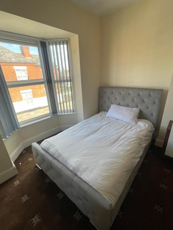 a bed in a bedroom with two windows at 1 Bedroom Flat - Milligan Road Leicester in Leicester