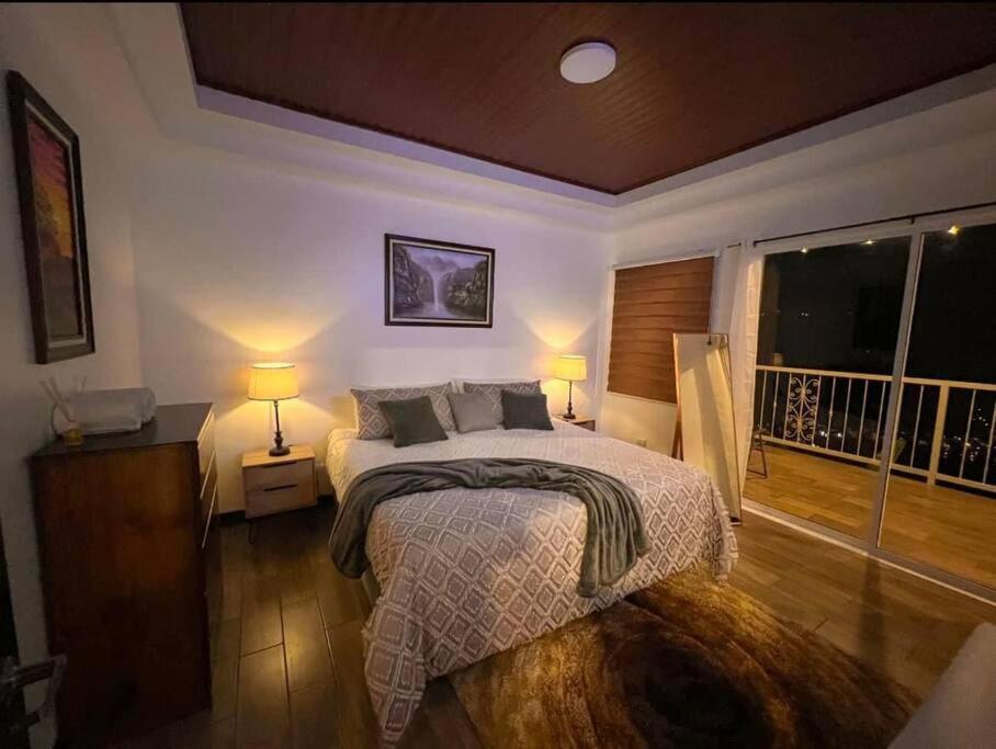 1 dormitorio con 1 cama con 2 lámparas y balcón en Orosi Mountain Lodge, en Orosí