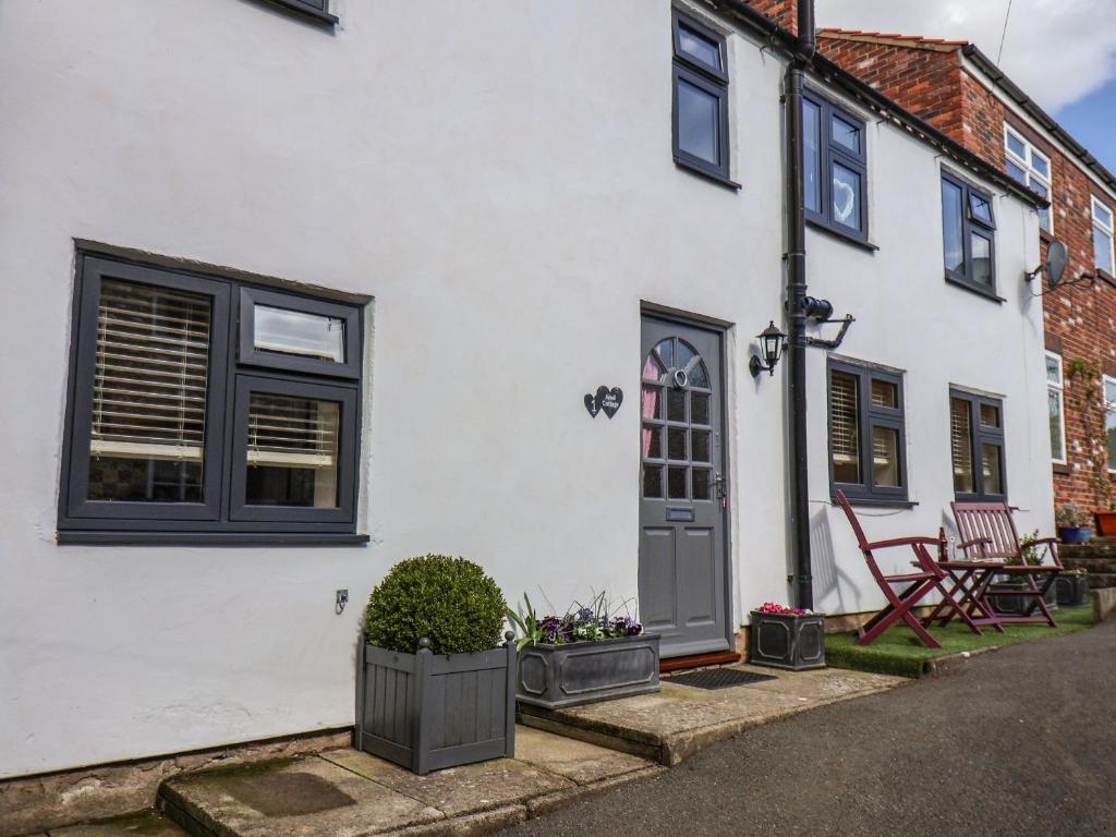 una casa bianca con finestre nere e una porta di Anvil Cottage a York