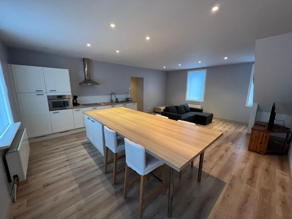 uma cozinha e sala de estar com uma mesa de madeira e cadeiras em Ruim app. met grote garage em Ypres